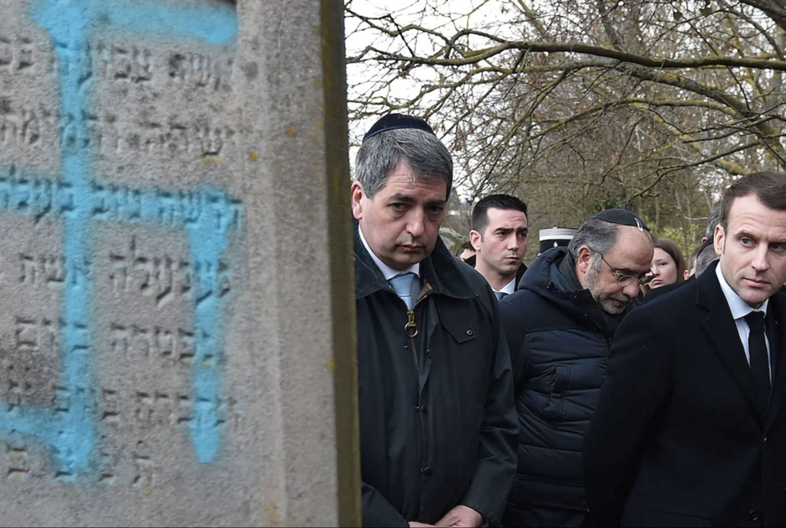 French President Emmanuel Macron looking at a grave vandalized with a swastika during a visit to the Jewish cemetery in Quatzenheim, France.