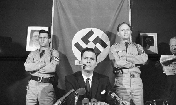 American Nazi Party founder George Lincoln Rockwell with paintings of Hitler and George Washington.